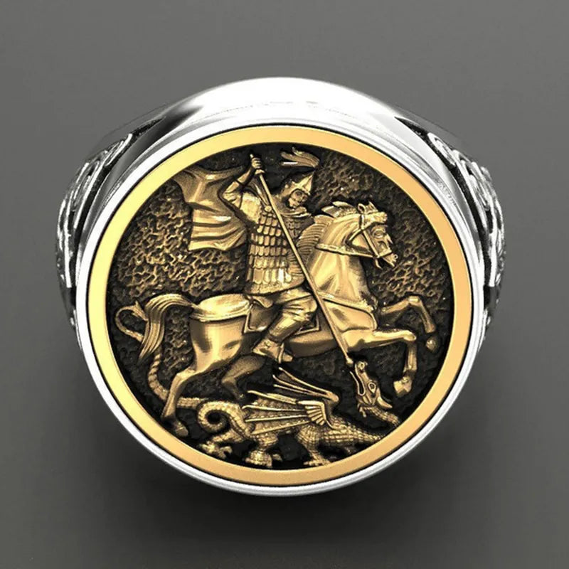 Anel masculino de São Jorge em aço prata com fundo cinza, mostrando o design detalhado e religioso.