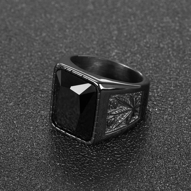 Anel masculino Black Weed com pedra Ônix, em fundo preto, com foco nos acabamentos laterais em aço preto.