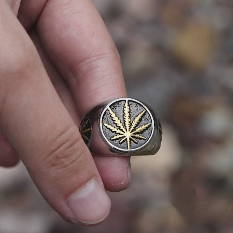 Close-up do detalhe da folha de maconha dourada em anel masculino de aço prata.