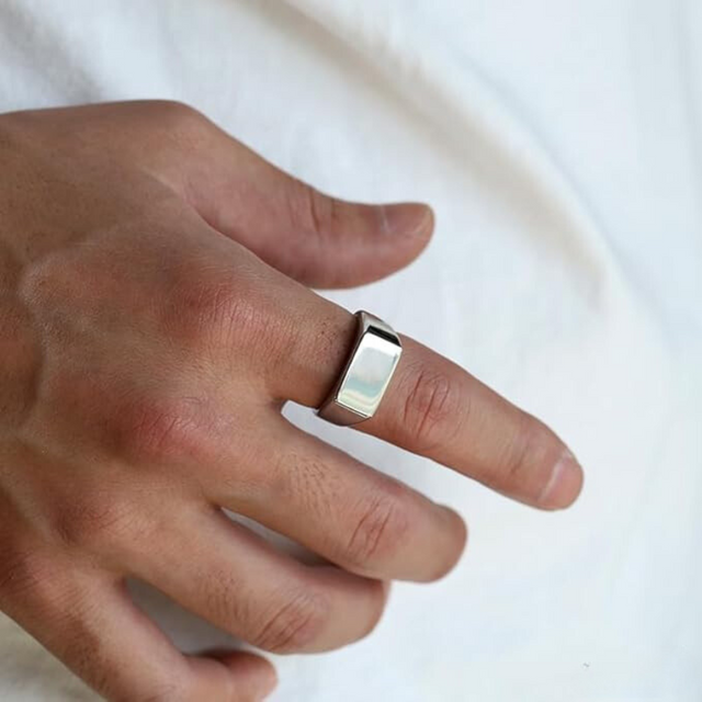 Anel masculino Flat Clássico em aço inoxidável prata focado na mão, mostrando seus detalhes simples e sofisticados.