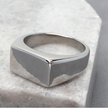 Anel masculino Flat Clássico em aço inoxidável prata posicionado sobre uma pedra branca, criando um contraste que valoriza seus detalhes.