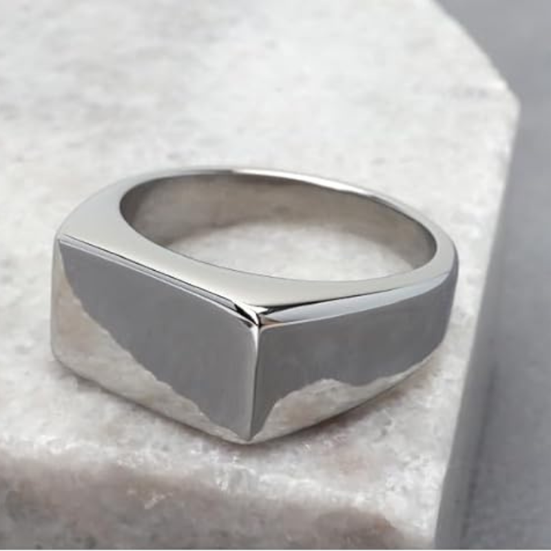 Anel masculino Flat Clássico em aço inoxidável prata posicionado sobre uma pedra branca, criando um contraste que valoriza seus detalhes.