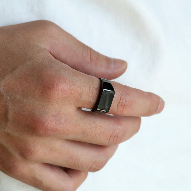 Anel masculino Flat Clássico em aço inoxidável preto focado na mão, mostrando seus detalhes simples e sofisticados