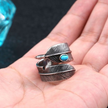 Anel masculino Pluma Turquesa em aço prata com detalhes de pena e pedra turquesa, mostrado na mão para destacar seu estilo vintage