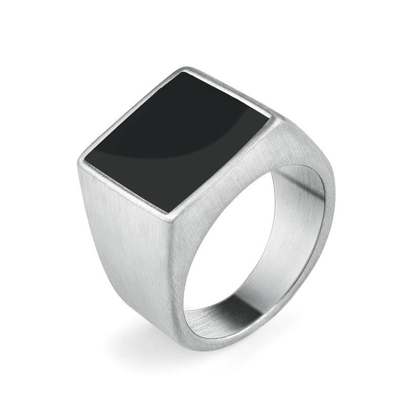 Anel masculino quadrado em aço prata com pedra preta lisa, exibido em fundo claro para destacar o contraste elegante entre a pedra e o metal.