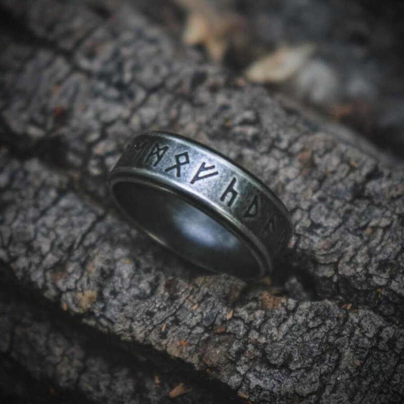 Anel masculino Norse Runes Viking em aço prata, apresentado em pé, enfatizando o brilho do material.