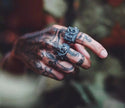 Mão tatuada usando o anel masculino Número Treze em aço preto, mostrando a combinação de estilo entre o anel e as tatuagens.