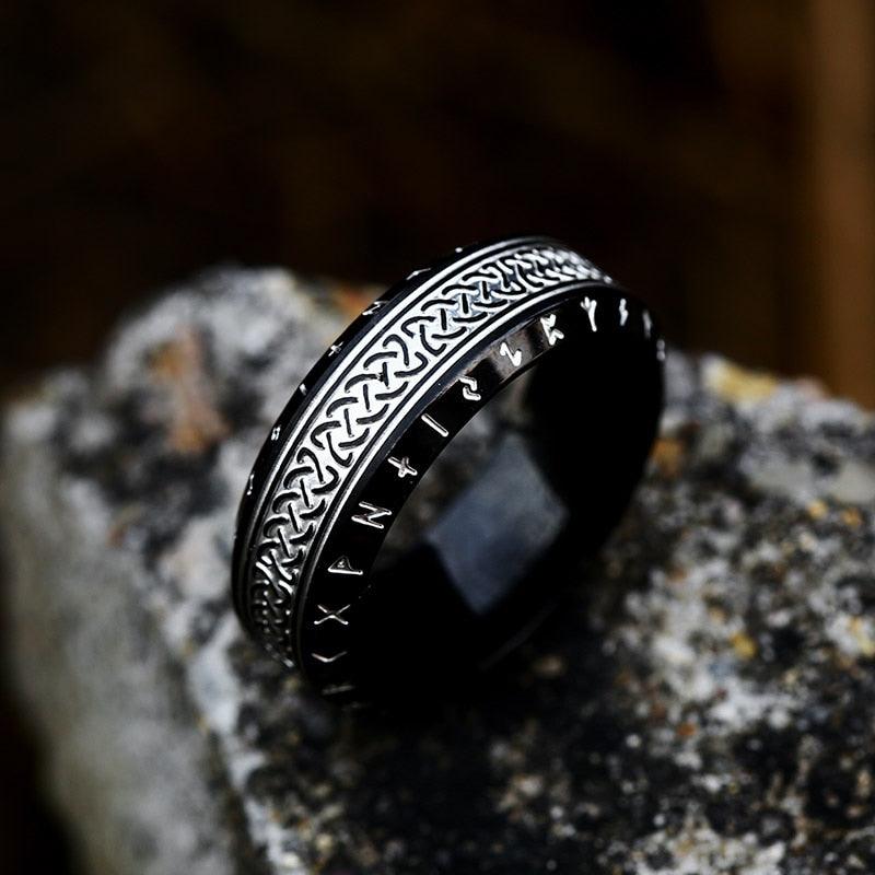 Anel masculino Guerreiro Viking em aço na cor preta, exibido sobre um fundo rochoso cinza, destacando seu acabamento escuro e design robusto.