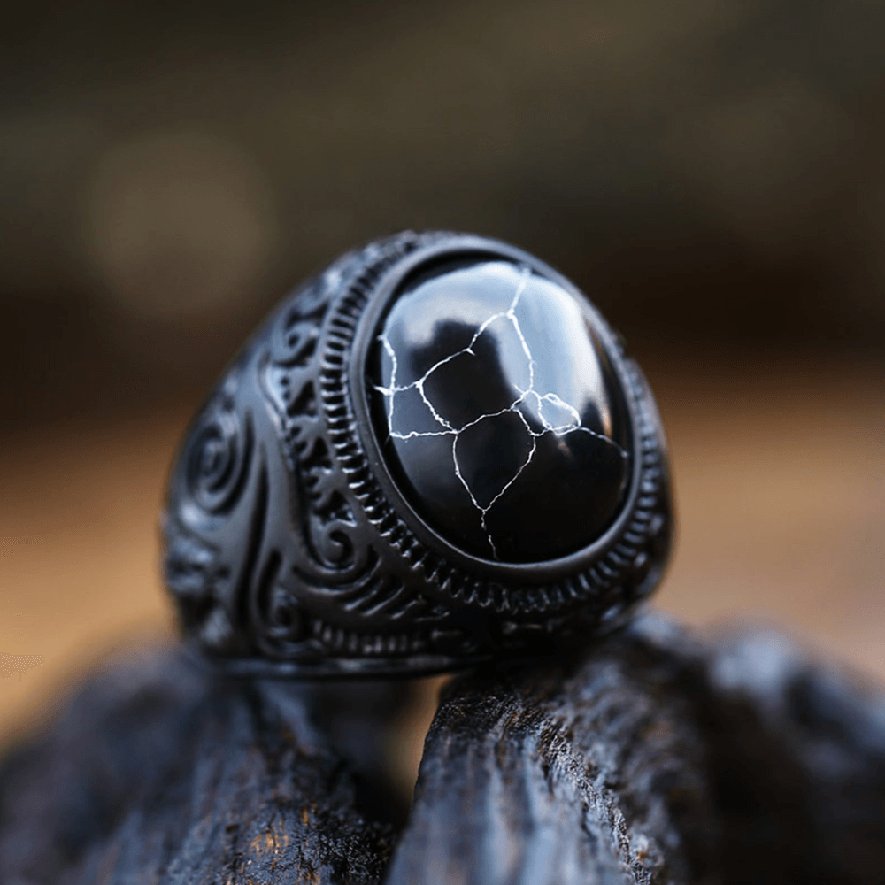 Anel masculino Inca Black com pedra texturizada, exibido em fundo preto, capturado de um ângulo lateral para destacar os detalhes do design.