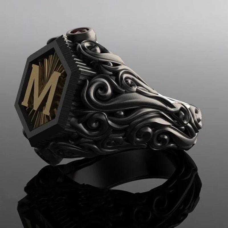 Anel masculino preto maçônico esculpido, visto de um quarto ângulo com fundo cinza escuro, destacando o acabamento e a estrutura elegante.