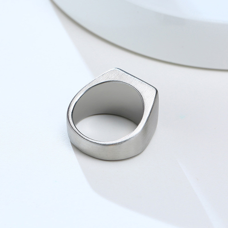 Anel masculino quadrado em aço prata com pedra preta lisa, mostrado de um ângulo diferente em fundo claro para capturar os detalhes do design